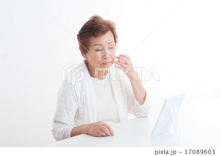 鏡で自分の顔を見ているシニアの女性 17089603