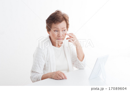 鏡で自分の顔を見ているシニアの女性 17089604