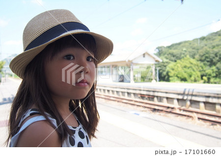 田舎の駅で電車を待つ可愛い女の子の写真素材