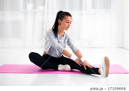 Fit woman doing aerobics gymnastics stretching exercises her leg and back to warm up at home on yoga Fit woman doing aerobics gymnastics stretching exercises her leg and back to warm up at home on yoga 17109668