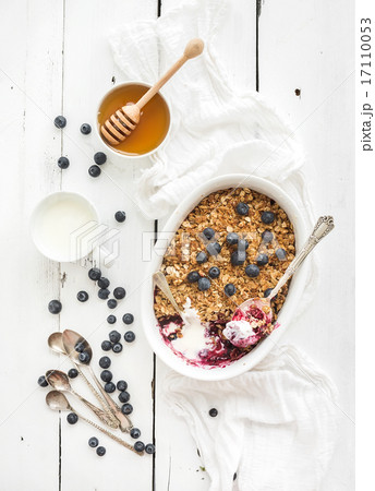 Healthy breakfast. Oat granola berry crumble with fresh blueberries, yogurt and honey in ceramic 17110053