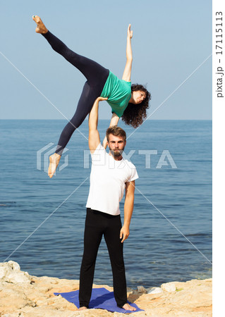 Couple girl and boy are practicing acroyoga on the sea Couple girl and boy are practicing acroyoga on the sea 17115113
