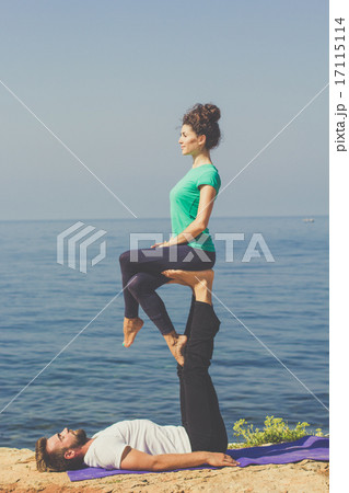 Couple are practicing acroyoga on the sea coast Couple are practicing acroyoga on the sea coast 17115114