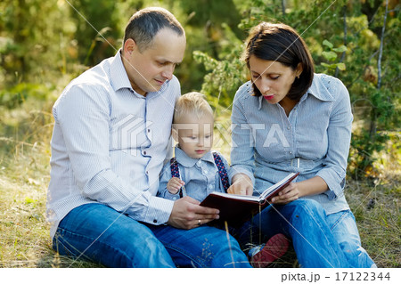 family reading book in park 17122344