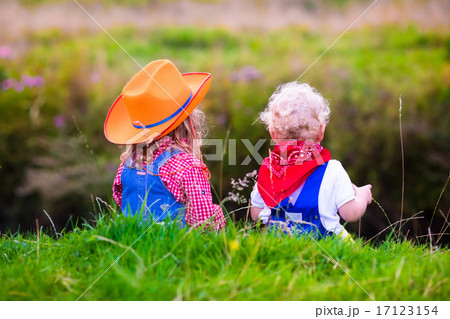 Little boy and girl dressed up as cowboy and cowgirl playing wit 17123154