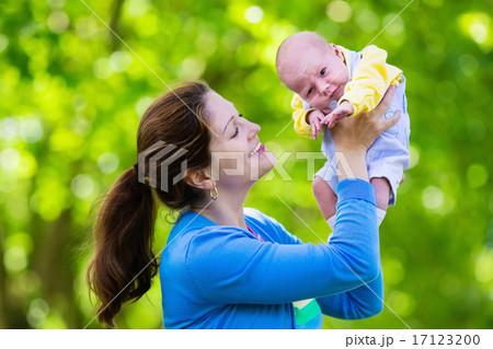 Mother holding newborn baby in a park 17123200