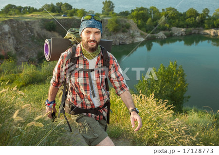 Young caucasian man with backpack walking on the top of hill 17128773