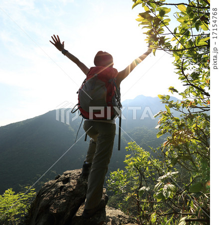 cheering woman hiker open arms at mountain peak 17154768