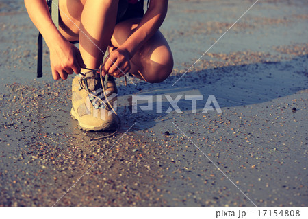 woman hiker tying shoelace on sunrise beach 17154808