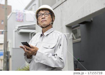 スマホをもつ　働くシニア男性　作業服　ヘルメット　現場 17155739