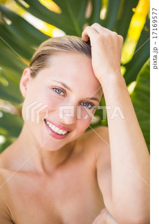 Beautiful blonde smiling at camera behind leaf 17169577