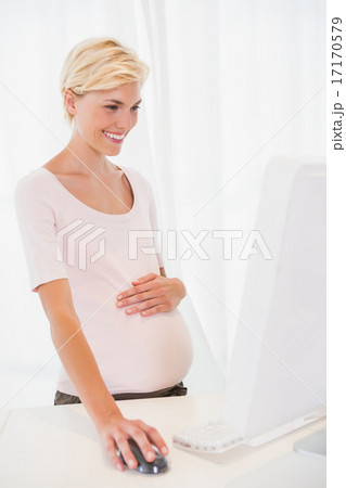 Smiling of a blonde pregnant using computer 17170579