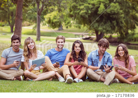 Happy friends in the park looking at tablet 17170836