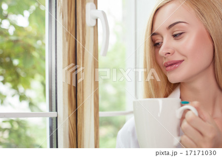 Beautiful young woman is resting on windowsill 17171030