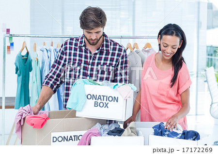 Smiling young friends volunteers separating clothes Smiling young friends volunteers separating clothes 17172269