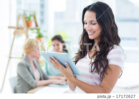 Smiling businesswoman using a tablet with colleagues Smiling businesswoman using a tablet with colleagues 17172627