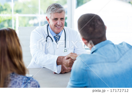 Smiling doctor greeting happy couple Smiling doctor greeting happy couple 17172712