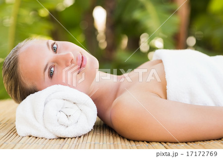 Peaceful blonde lying on bamboo mat with flowers 17172769