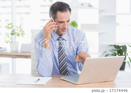 businessman phoning at his desk 17174446