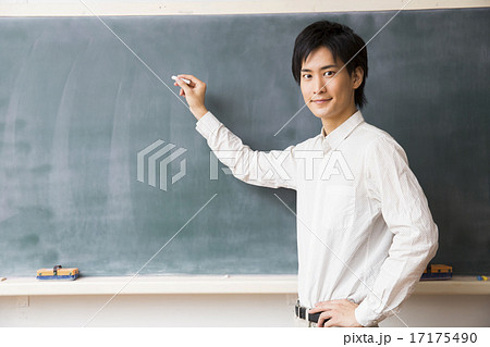 黒板の前に立つ若い男性教師の写真素材