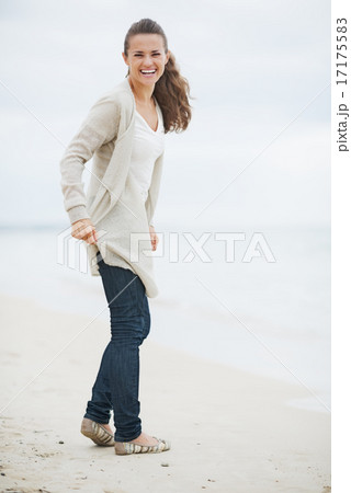 Happy young woman in sweater walking on lonely beach 17175583