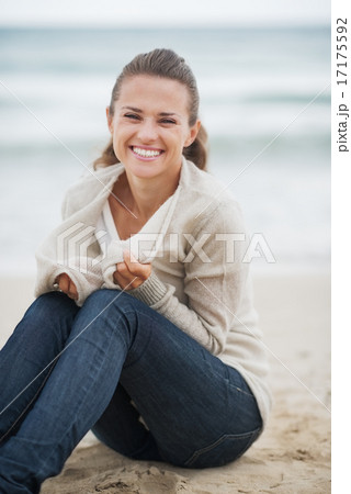Happy young woman wrapping in sweater while sitting on lonely be Happy young woman wrapping in sweater while sitting on lonely be 17175592