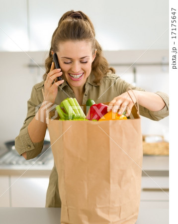 Young housewife sort purchases after shopping and talking cell p 17175647