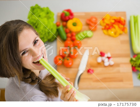 Happy young woman eating celery in modern kitchen 17175730