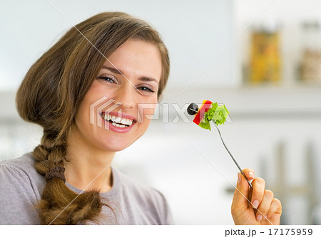Portrait of smiling young housewife eating vegetables Portrait of smiling young housewife eating vegetables 17175959