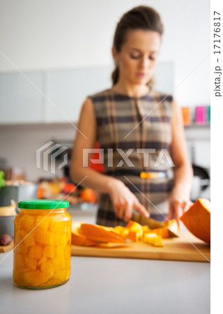 Closeup on jar of pickled pumpkin and young housewife cutting in 17176817