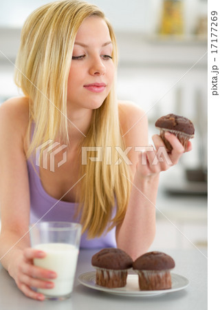 Teenager girl eating muffin with milk in kitchen Teenager girl eating muffin with milk in kitchen 17177269