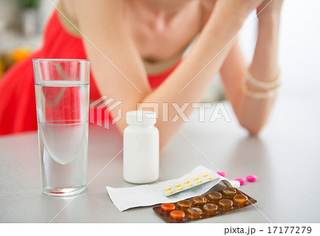 Closeup on pills on table and young woman in background 17177279