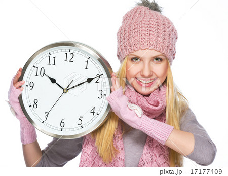 Happy teenager girl in winter hat and scarf showing clock 17177409