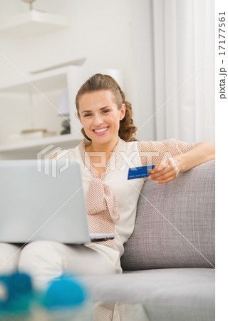 Smiling young housewife with laptop and credit card in living ro Smiling young housewife with laptop and credit card in living ro 17177561