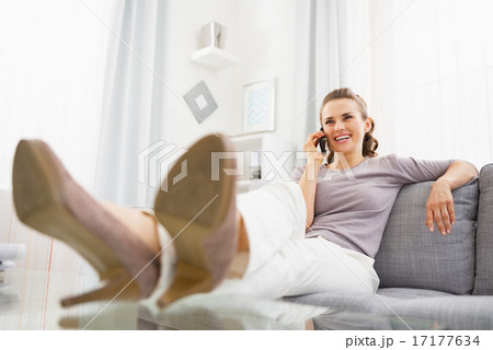 Smiling young woman talking cell phone in living room 17177634