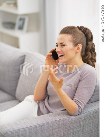 Happy young woman talking mobile phone in living room Happy young woman talking mobile phone in living room 17177865
