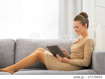 Young woman sitting on sofa and using tablet pc 17178003