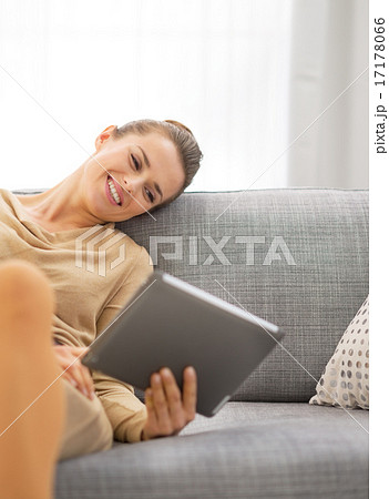 Young woman sitting on sofa and using tablet pc 17178066