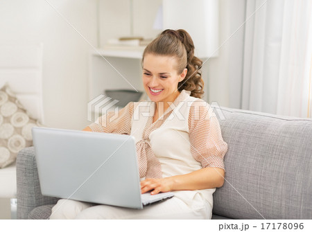 Young housewife using laptop in living room Young housewife using laptop in living room 17178096