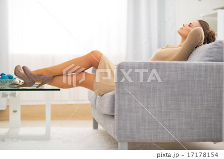 Relaxed young housewife laying on divan in living room 17178154