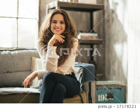 Happy young woman sitting in loft apartment 17178221