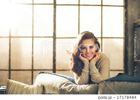Brunette leaning over sofa smiling, resting chin on hands 17178484