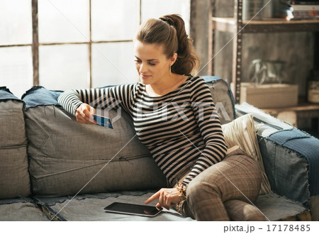 Young woman with credit card using tablet pc in loft apartment 17178485