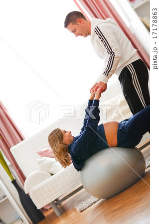 Young husband helping his pregnant wife doing exercise on fitnes 17178863