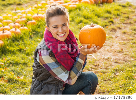 Portrait of happy young woman showing pumpkin 17178890