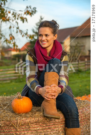 Portrait of smiling young woman sitting on haystack with pumpkin Portrait of smiling young woman sitting on haystack with pumpkin 17178969