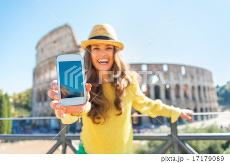 Closeup on happy young woman showing cell phone in front of colo 17179089