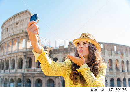 Woman tourist taking selfie blowing kisses at Rome Colosseum 17179178