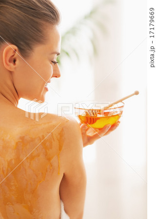Smiling young woman holding plate with honey. rear view 17179669