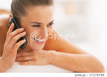 Portrait of young woman laying on massage table and talking cell Portrait of young woman laying on massage table and talking cell 17179789